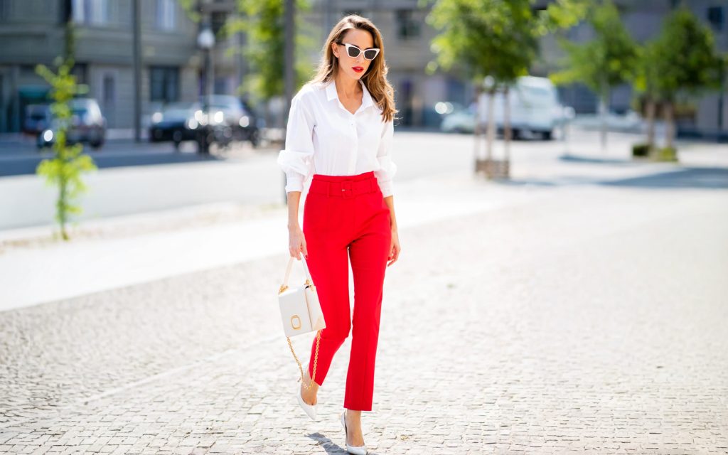 Boja koja podiže samopouzdanje: 25 proljetnih kombinacija koje će vas oduševiti Žena u crvenim hlačama visokog struka i bijeloj košulji na ulici