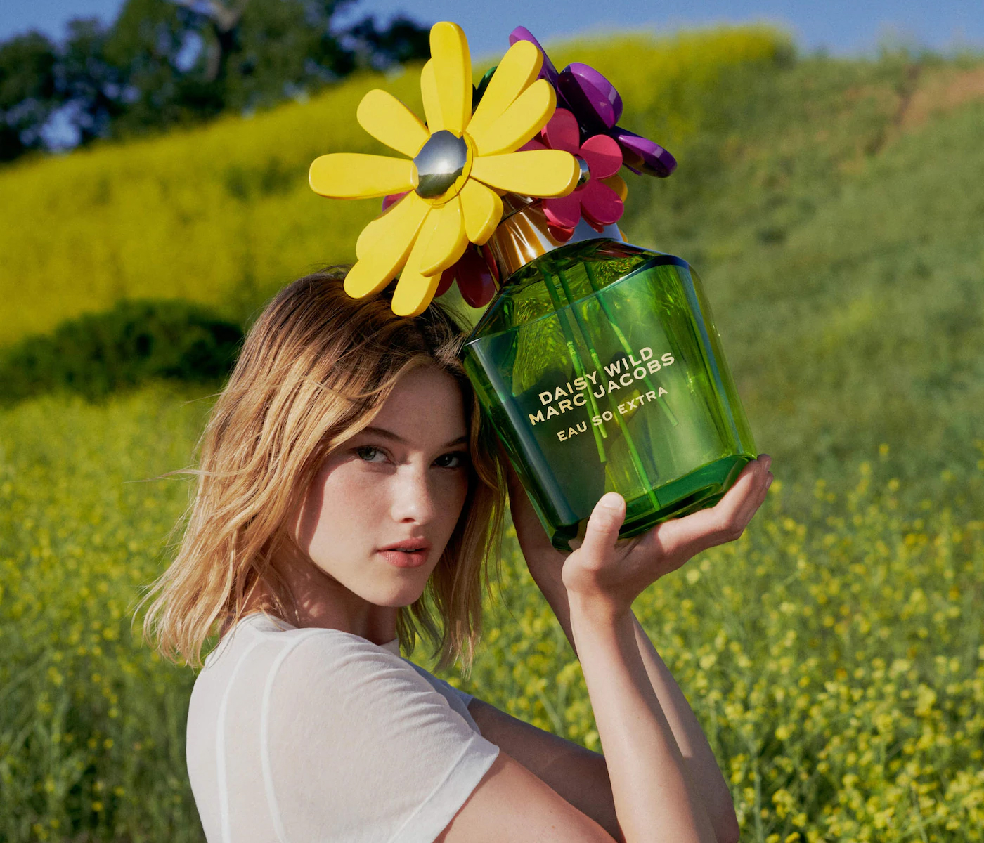 Marc Jacobs Daisy Wild Eau So Extra parfem u zelenoj bočici sa čepom ukrašenim žutim, ljubičastim i roze cvjetovima.