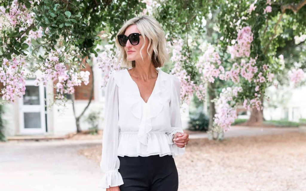 Žena u bijeloj bluzi sa karnerima i crnim hlačama, proljećni modni trend 2026