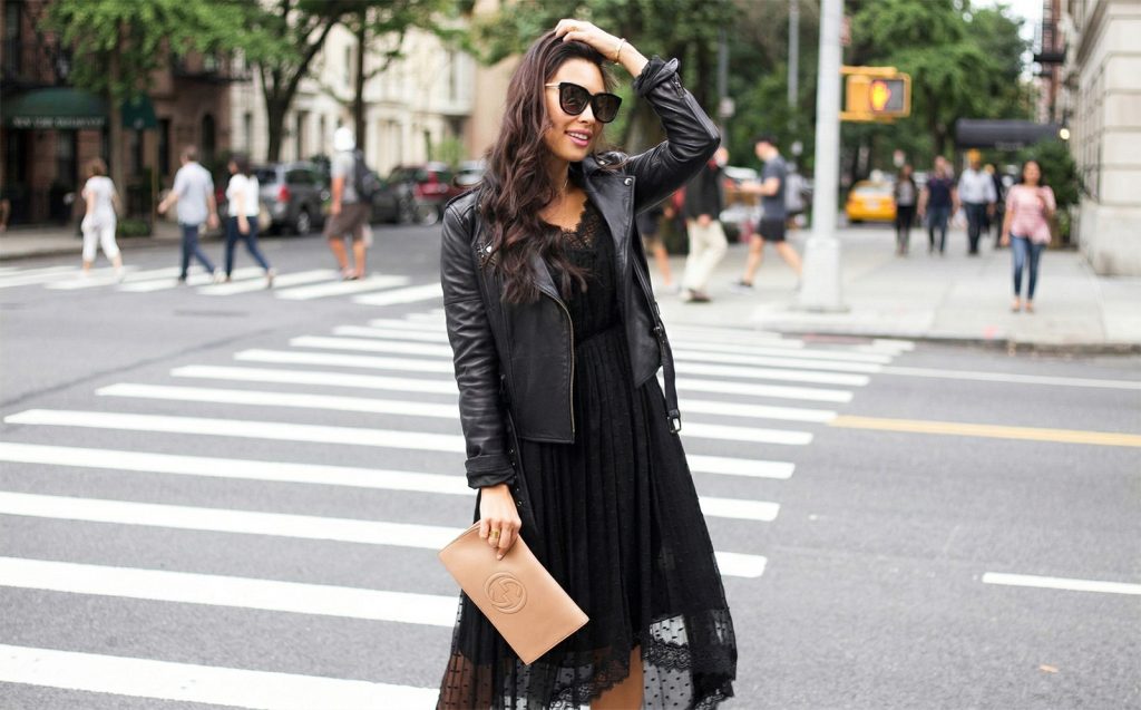 Ovo su najpopularnije kožne jakne za proljeće Moderna žena u crnoj čipkastoj haljini i kožnoj jakni prelazi pješački prijelaz u gradu, noseći bež Gucci torbicu i sunčane naočale.