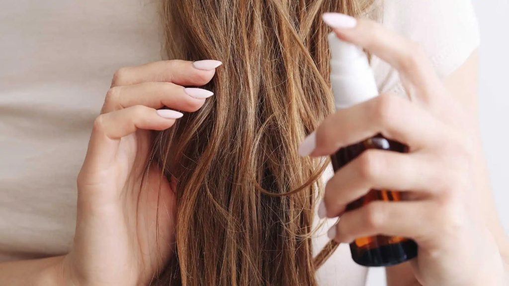 Žena nanosi sprej za njegu na kosu poslije pranja.