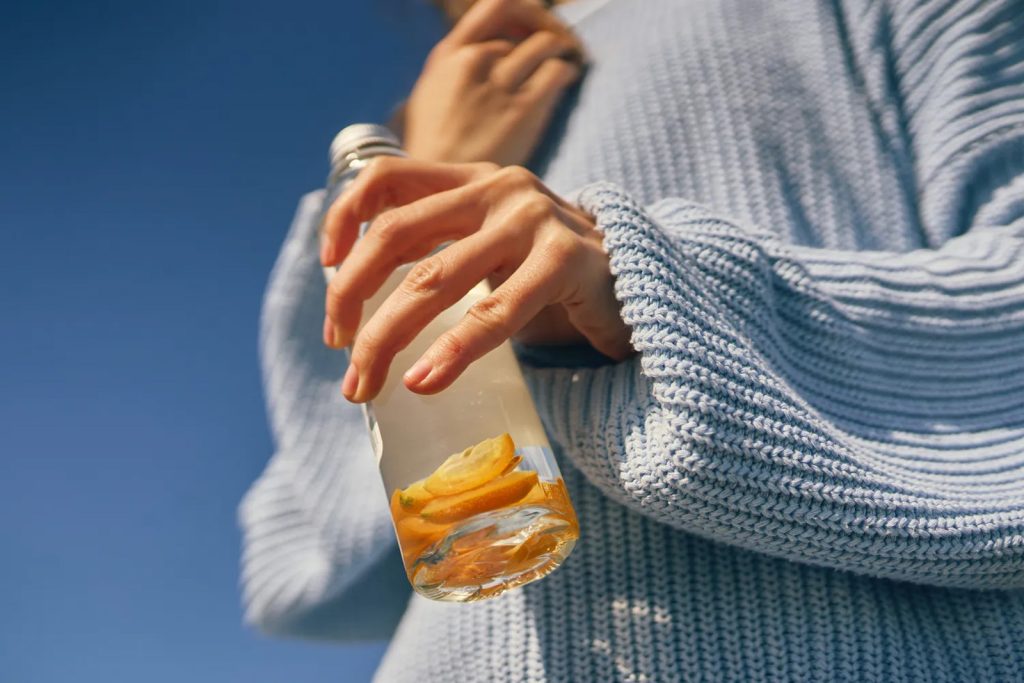 5 napitaka koji mogu pomoći zdravlju jetre (a nisu voda) Žena drži bocu aromatizovane vode sa kriškama citrusa